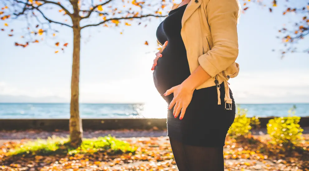 Pregnant woman holding her stomach outdoors.
